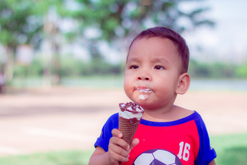 Cute Toddler boy Eating Ice-Cream. asian little boy are happiness  and funny in park at thailand