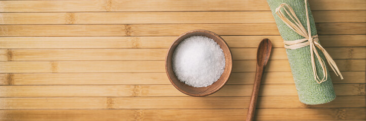 Bath salts spa wellness banner background. Top view of objects on bamboo texture. Exfoliation towel...