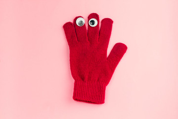 top view red  glove  with googly eyes isolated  on a pink background