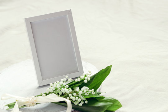 empty mock up photo frame and bouquet of lilies of the valley