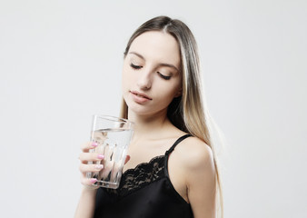 lifestyle, health and people concept - young woman wearing pajamas holding water glass