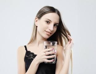 lifestyle, health and people concept - young woman wearing pajamas holding water glass