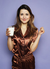 lifestyle, health and people concept: beautiful girl dressed in pajamas drinking milk