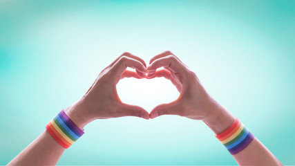 LGBT pride or LGBTQ+, LGBTQIA+, Gay pride with rainbow wrist band on hands in heart-shapefor...