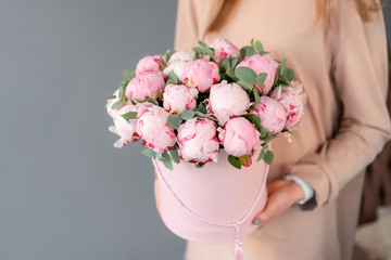 Pink peonies in pink round box. Beautiful peony flower in womans hands for catalog or online store....