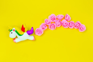 top view flat lay creative still life with flying unicorn and tropical flowers isolated on a yellow background