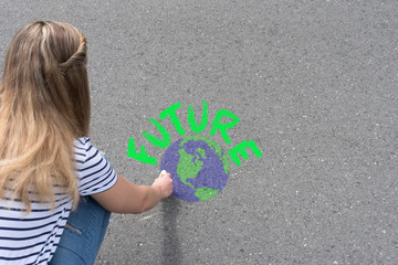Eine junge Frau malt das Erdball und Wort Future auf die Straße