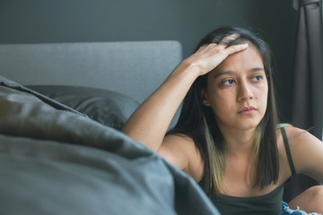 Young dark-haired girl sits about a bed alone