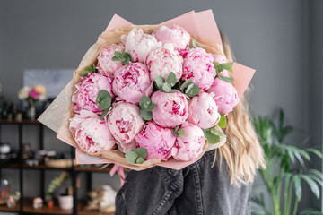 Pink peonies in womans hands. Beautiful peony flower for catalog or online store. Floral shop...