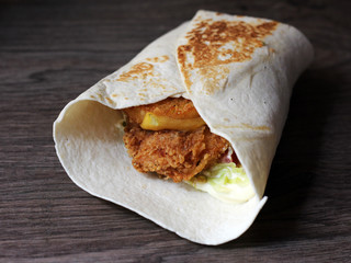 Shawarma sandwich, fresh roll of thin lavash filled with grilled meat, mushrooms, cheese, cabbage, carrots, sauce, green. Traditional Eastern snack.