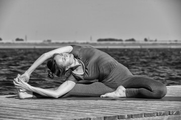 Fototapeta na wymiar Woman making yoga exercise at a lake. Black and white image