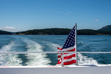 American flag flying off the back of a boat on the Salish Sea in the San Juan Islands on sunny blue...