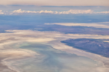 Aerial view from airplane of the Great Salt Lake in Rocky Mountain Range, sweeping cloudscape and landscape during day time in Spring. In Utah, United States.