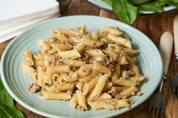 Penne pasta with minced meat on a blue plate