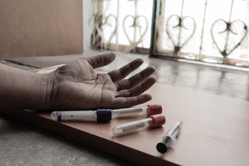 Drug Addict hand with syringe on the floor with a tubes of drugs.