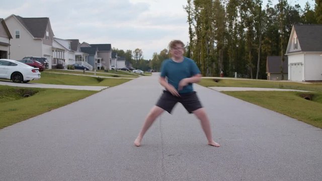A young boy doing Fortnite dances in the street.
