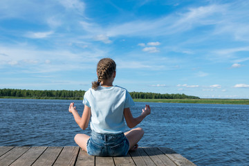 girl doing yoga in nature by the lake