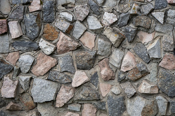 The wall of natural stone. Masonry of cobblestones bonded with cement. Texture.