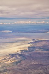 Aerial view from airplane of the Great Salt Lake in Rocky Mountain Range, sweeping cloudscape and landscape during day time in Spring. In Utah, United States.