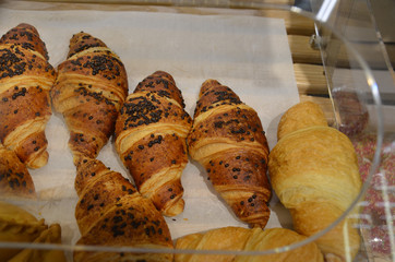 Delicious creamy croissant on paper in the window of the pastry shop, delicious pastries. Close-up of Croissants on shelf in bakery shop. Fresh baked croissant pastry on sale in cafe