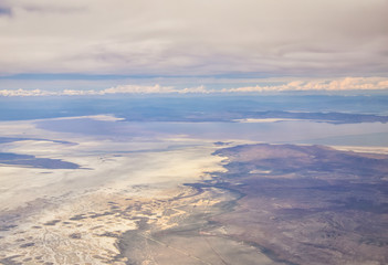 Aerial view from airplane of the Great Salt Lake in Rocky Mountain Range, sweeping cloudscape and landscape during day time in Spring. In Utah, United States.