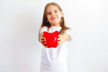 Children holds a red piggy Bank with a coin. Concept of cash savings.