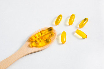 Capsules of omega vitamins on a wooden spoon on a white background with place for text. The concept...