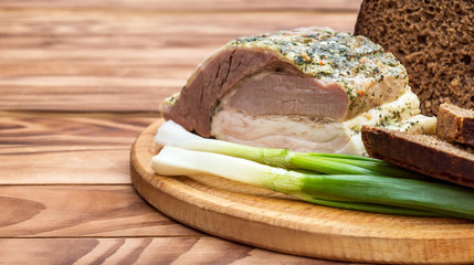 Baked meat with rye bread and green onion on cutting board. Close up. Space for text