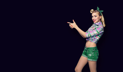 woman, dressed in pin-up style, showing something or copyspace, over black color background