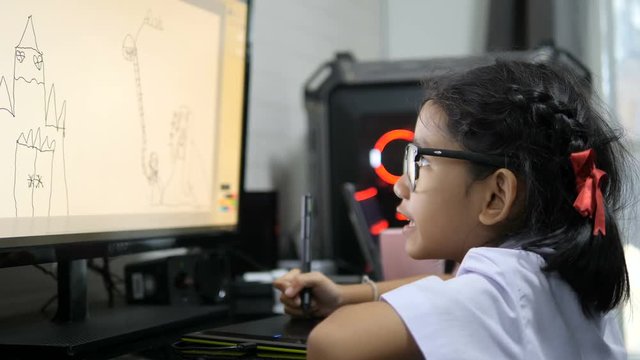 Asian little girl in Thai student uniform using pen tablet to drawing and digital painting with computer