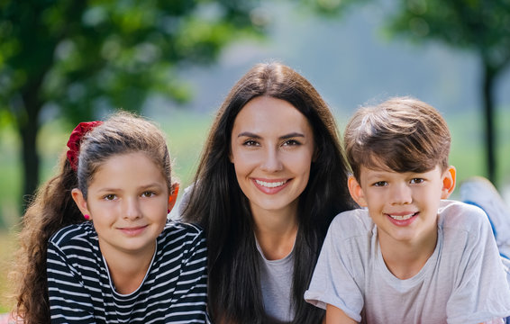 Portrait picture of beautiful young mother with two children outdoors