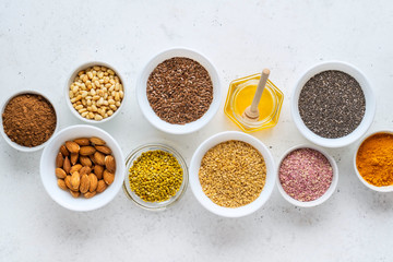 Healthy super food clean eating selection (seeds, powder turmeric, carob, nuts, honey, bee pollen, dried beet)