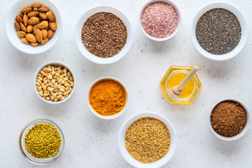 Healthy super food clean eating selection (seeds, powder turmeric, carob, nuts, honey, bee pollen, dried beet)