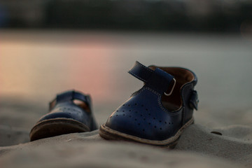 child boots in the sand, shore in the evening