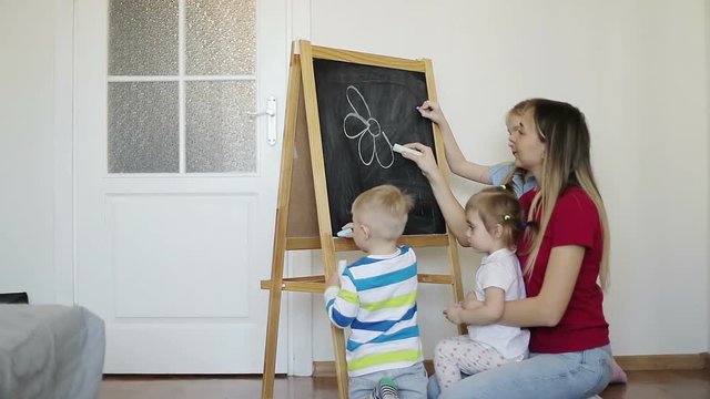 Happy family draws with crayons on the blackboard at home.