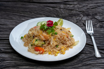 Fried rice with shrimps and vegetables in a white dish on an old wooden table, close up . Thai food , Thai cuisine