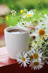 A cup of tea with daisies bouquet