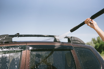 A man washes a car with a high pressure washer
