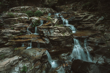 Obraz premium Running stream cascades over rocks waterfalls in Macquarie Pass wilderness of Australia