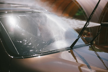 A man washes a car with a high pressure washer