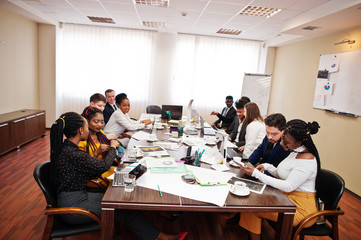 Multiracial business team addressing meeting around boardroom table.