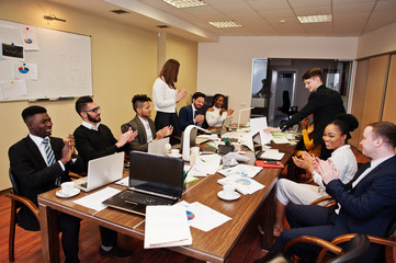 Multiracial business team meeting around boardroom table, clap hands.