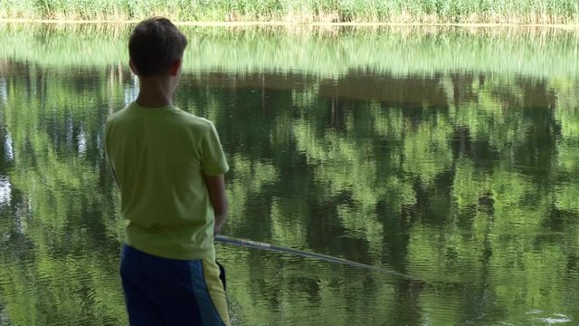 teen child catches a fishing rod on the pond.
