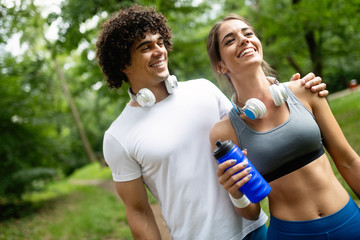 Athletic couple friend drinking water after running