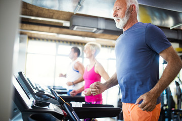 Fototapeta na wymiar Senior people running on a treadmill in health club.