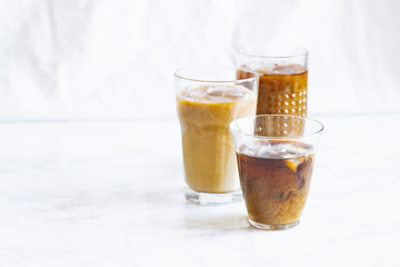 Iced coffee with cream and vanilla in various glasses on white background. Summer cocktail or dessert