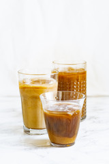 Iced coffee with cream and vanilla in various glasses on white background. Summer cocktail or dessert