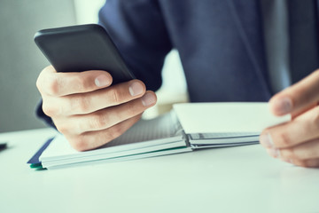 Businessman holding blank business card and dialing numbers on mobile phone