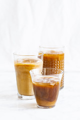 Iced coffee with cream and vanilla in various glasses on white background. Summer cocktail or dessert