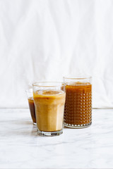 Iced coffee with cream and vanilla in various glasses on white background. Summer cocktail or dessert